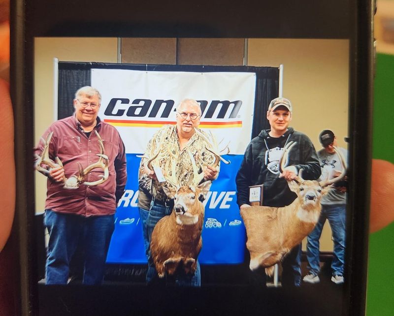 A photo shows Richard Waters of Markesan, center, with the white-tailed deer he presented to measurers in March. A DNR investigation determined the rack came from a farmed animal.