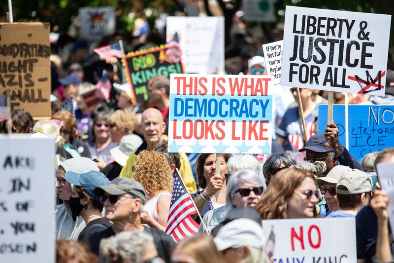 Protest attendees holding their signs at the No Kings’ Protest, held at Cathedral Square Park in Milwaukee, on June 14, 2025. More than 100 pro-democracy advocacy groups worked together to organize "No Kings" protests, with actions planned in more than 1,500 cities nationwide, including Milwaukee.