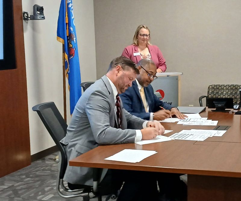 Fox Valley Technical College president Chris Matheny (left) signs an articulation agreement with University of Wisconsin-Stevens Point chancellor Thomas Gibson (center) as FVTC vice president Jennifer Lanter looks on June 17, 2025 at FVTC.
