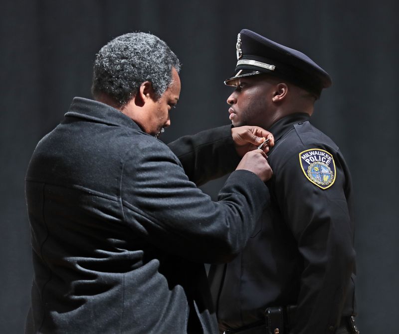 New MPD officer Kendall Corder gets his badge pinned on by his father Raymond Corder at the Milwaukee Police Department graduation ceremony at the Milwaukee Safety Academy on December 12, 2019.