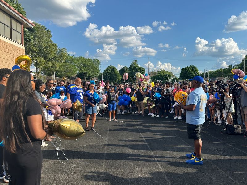 Rufus King International High School running backs coach Theo Carney presents a football signed by the team to Nate White's parents during a balloon release remembering the former star player July 2 at the school. White, a 20-year-old former University of Wisconsin football player and Rufus King graduate, died June 25 at his apartment in Brookings, South Dakota.