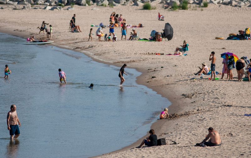 People take in the beach at Deland Park along Lake Michigan, Tuesday, July 1, 2025, in Sheboygan, Wis.