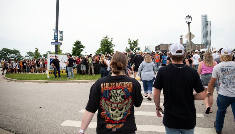 Festival attendees making calls to let others know that an evacuation has taken place during the Harley-Davidson Homecoming Festival at Veterans Park, causing the streets to be crowded with festival goers on July 11, 2025.