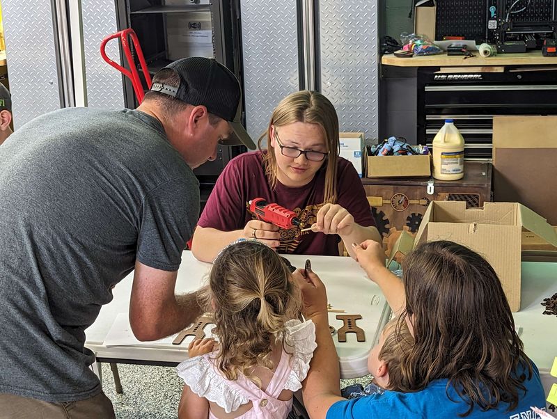 Elijah A., STEAMpunk member, glues the wheels on a rubber band car for STEAM on the Lakeshore attendees.