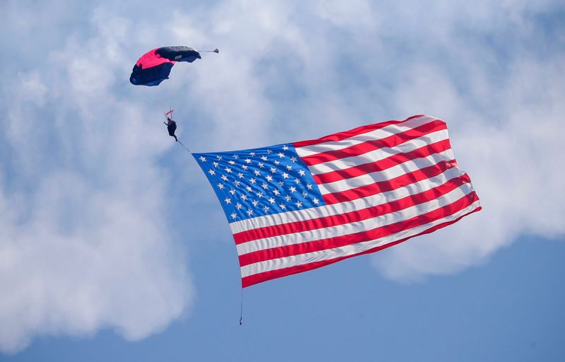 The Flag of the United States gently comes down to earth to kick off the afternoon air show during the opening day of EAA AirVenture 2025 at Wittman Regional Airport, Monday, July 21, 2025, in Oshkosh, Wis.