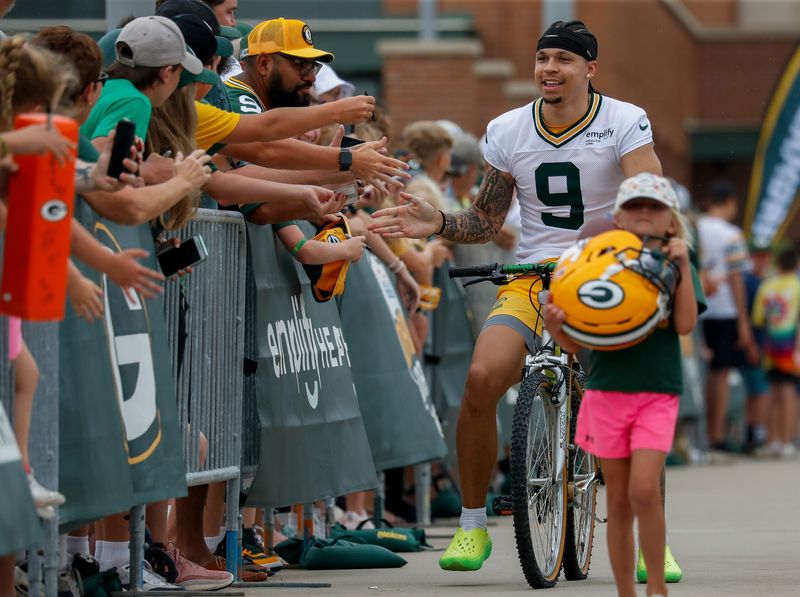 Green Bay Packers wide receiver Christian Watson (9) slaps hands with fans as he rides a bicycle to practice during the first day of training camp on Wednesday, July 23, 2025, at Ray Nitschke Field in Ashwaubenon, Wis. 
Tork Mason/USA TODAY NETWORK-Wisconsin