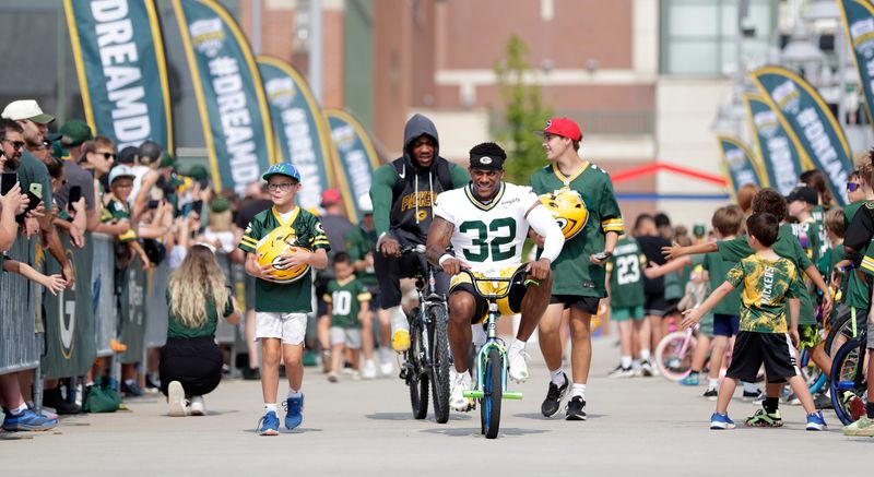 Green Bay Packers running back MarShawn Lloyd (32) rides a fan's bicycle while participating in the Drive Drive on the third day of training camp July 25, 2025, in Green Bay, Wis.