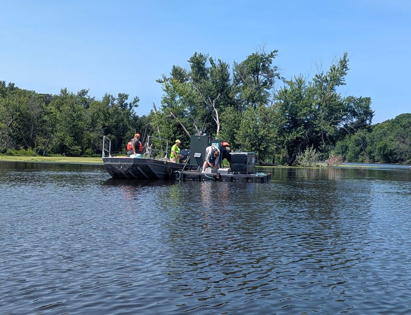 Scientists from the U.S. Geological Survey and Wisconsin and Minnesota Departments of Natural Resources assemble monitoring equipment in July 2025 on automatic feeders that will float in the Mississippi River to bait invasive carp.