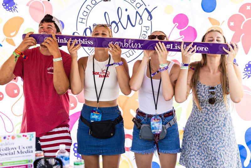 Festival-goers line up for a round of Shotski fun at the Carbliss station at XRoads41 in Oshkosh Aug. 7, 2025.