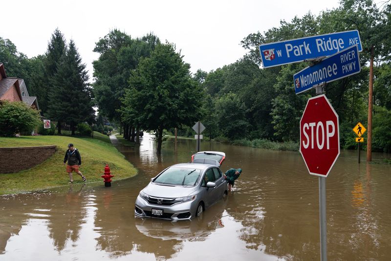 Marty Honel helps his neighbors push Linda Bradshaw’s daughter’s car out of the flood waters on Menomonee River parkway in Wauwatosa, August 10, 2025. Milwaukee had 14.55 inches within a 24-hour period causing widespread flooding and millions of dollars of damage.