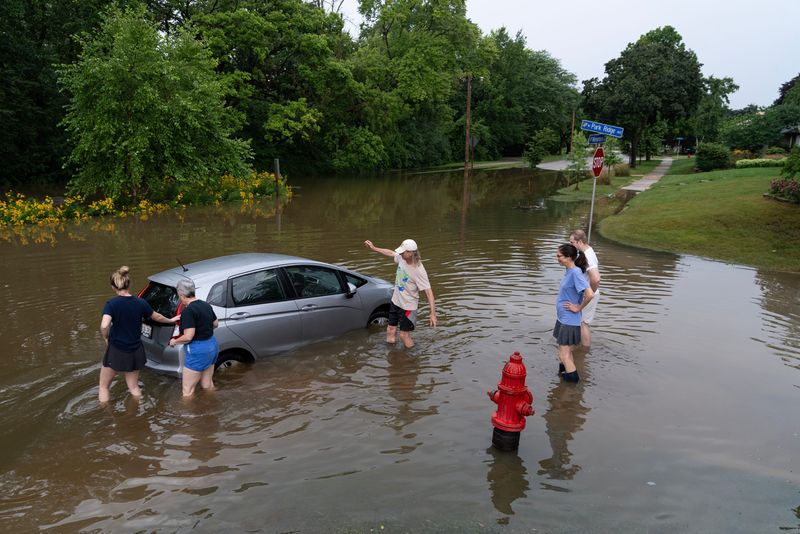 Neighbors gather to help Linda Bradshaw push her daughter’s car out of the flood waters on the Menomonee River parkway.