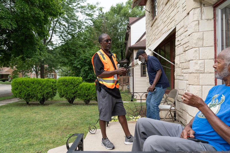 Tony Jones of the Milwaukee County ADRC speaks with Donald McNealy and David Noblin about flood damage in their basement, while door knocking in the area, in Milwaukee on the afternoon of Aug. 12, 2025.