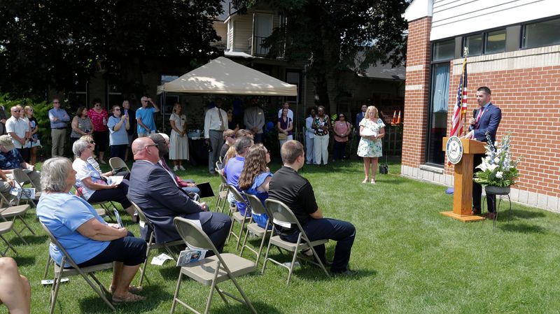 District Attorney Eric Toney, right, speaks before an assembled crowd in front of the Kiel Post Office, Friday, Aug. 15, 2025, in Kiel, Wis. The Kiel U.S. Post Office was named in memory of Wisconsin State Trooper Trevor J. Casper.