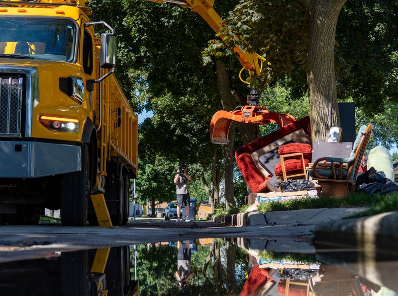 Department of Public Works crews dispose of flood-damaged personal belongings of Collette McDougal on August 21, 2025, in Milwaukee.