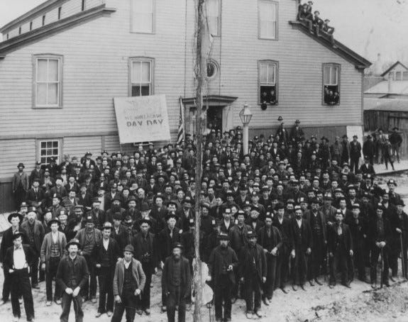 Two Rivers Manufacturing Company workers on strike gathered in front of Turner Hall in 1895. The sign reads 'WE WANT A CASH PAY DAY.'