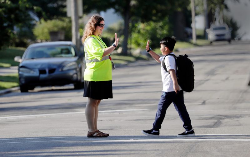 A Madison Elementary School crossing guard greets a student on the first day of classes, Tuesday, Sept. 2, 2025, in Manitowoc, Wis.