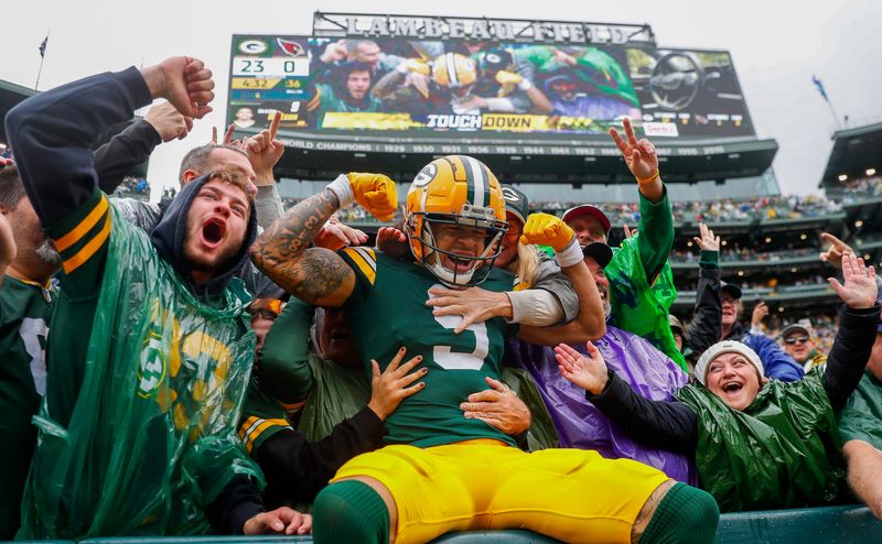 Oct 13, 2024; Green Bay, Wisconsin, USA; Green Bay Packers wide receiver Christian Watson (9) flexes as he does the “Lambeau Leap” with Packers fans after scoring a touchdown against the Arizona Cardinals at Lambeau Field. Mandatory Credit: Tork Mason/USA TODAY NETWORK-via Imagn Images