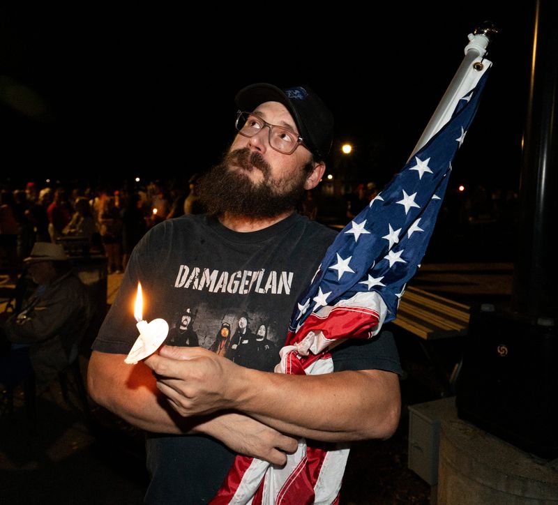 Branko Meyer of Waukesha holds a candle and the U.S. Flag during a Remembering Charlie Kirk vigil hosted by the Wisconsin Young Republicans at Cutler Park on Tuesday September 16, 2025 in Waukesha, Wisconsin.