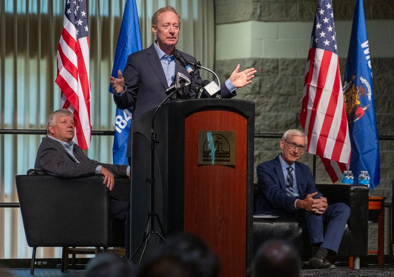 Brad Smith, Microsoft president and vice chair speaks as Mount Pleasant Village President Dave DeGroot (left) and Gov. Tony Evers listen during a press event at the Racine Civic Centre in Racine, Wisconsin on Sept. 18, 2025. Microsoft announced plans to spend $4 billion to build a second data center in Mount Pleasant that it says will be the most advanced AI center in the world.