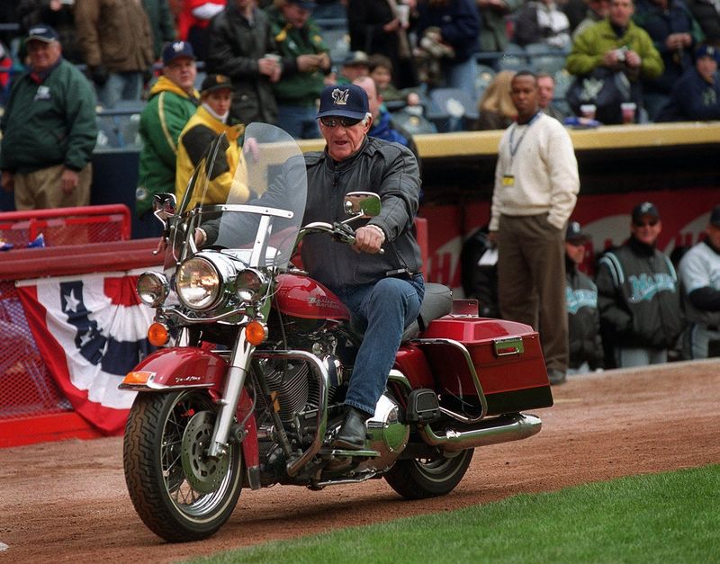 Bob Uecker makes a grand entrance on a Harley-Davidson motorcycle for the final home opener at County Stadium Monday, April 10. 2000. Uecker threw out the first pitch.