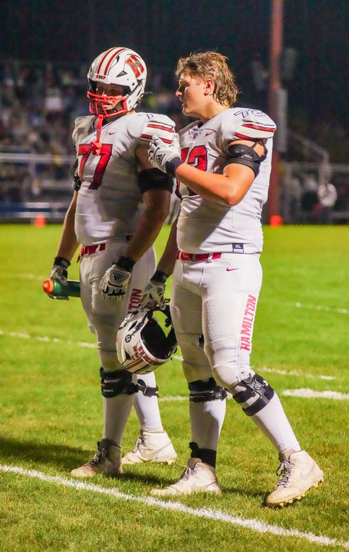Sussex Hamilton linemen Hunter Mallinger (77) and Reece Mallinger talk on the field at a 2025 game.