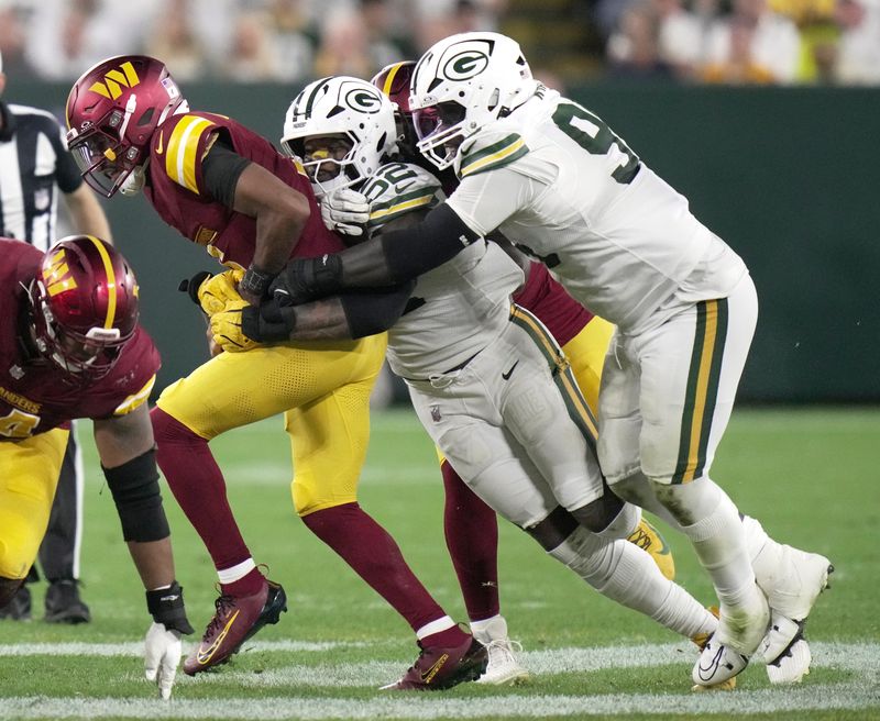 Sep 11, 2025; Green Bay, Wisconsin, USA; Washington Commanders quarterback Jayden Daniels (5) is sacked by Green Bay Packers defensive end Rashan Gary (52) and defensive tackle Devonte Wyatt (95) during the third quarter at Lambeau Field. Mandatory Credit: Mark Hoffman-USA TODAY Network via Imagn Images