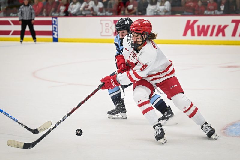 Wisconsin defender Ava Murphy (9) lunges for a loose puck in front of the Maine goal during the first period in a game Friday, October 3, 2025, at LaBahn Arena in Madison, Wisconsin.