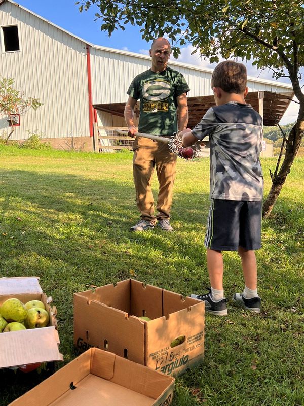 Ross Hardie holds the apple picker while his son Samuel empties it.
