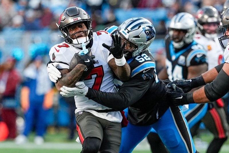Dec 1, 2024; Charlotte, North Carolina, USA; Tampa Bay Buccaneers running back Bucky Irving (7) is tackled by Carolina Panthers linebacker DJ Johnson (52) during the first quarter at Bank of America Stadium. Mandatory Credit: Jim Dedmon-Imagn Images