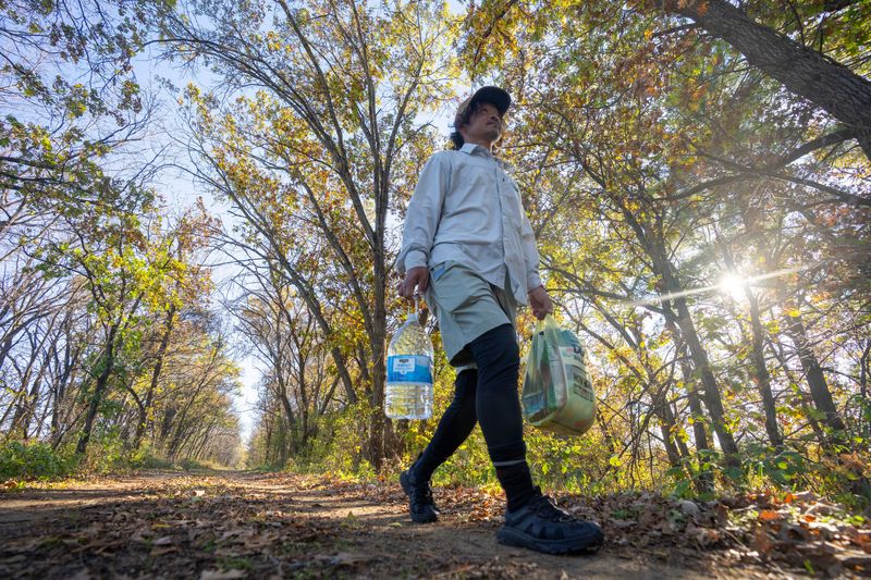 After buying food and charging his phone at a nearby store, Masafumi Saito walks a mile back to his tent along the Sugar River Trail, which is a segment of the Ice Age National Scenic Trail, Monday, October 27, 2025 in Albany, Wisconsin. Saito traveled from his native Japan to hike the entire trail from west to east.
