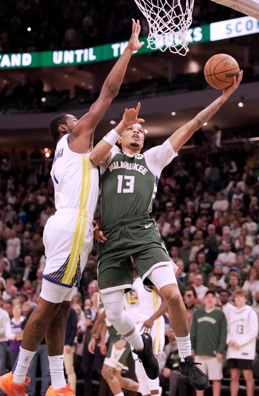 Milwaukee Bucks guard Ryan Rollins (13) scores against Golden State Warriors forward Jonathan Kuminga (1) during the first half Oct. 30 at Fiserv Forum.