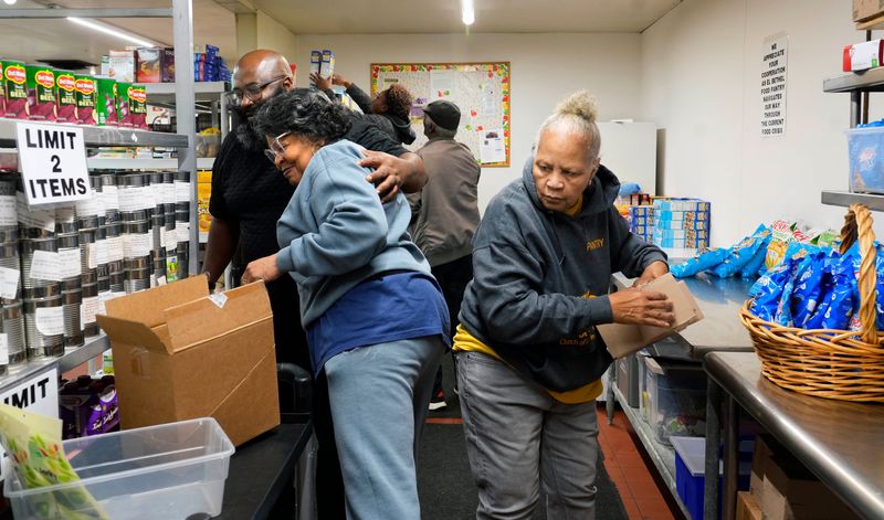 Roger King, left, stops to give Effie Renfro, center, a hug on Friday, Oct. 31, 2025 at El-Bethel Church of God in Christ's food pantry at 5401 W. Good Hope Road. Also helping in the food pantry is Agnes Wallace, right. The church has seen an increase with families needing assistance at the food pantry. The church was also the site of today's press conference held by Milwaukee Democrats to address how Milwaukee families and others will be affected when SNAP benefits stop because of the government shutdown.