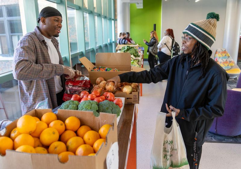 Tim Wright (right), an MATC culinary student from Milwaukee, selects fresh fruits vegetable as volunteer Justin Maclin assists, as part of a CommUnity Day at the MATC Downtown Campus Main Building in Milwaukee, Wisconsin on Nov. 5, 2025. The produce was made available by Sherman Park Grocery Store on West Fond du Lac Avenue.