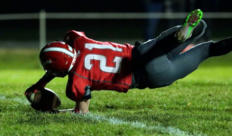 Manitowoc Lutheran's Josiah Martin (21) lands in the end zone against Cedar Grove-Belgium, Friday, November 7, 2025, in Manitowoc, Wis.