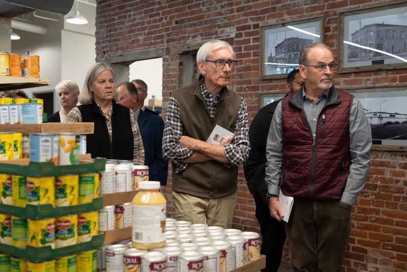 Rep. Tara Johnson and Gov. Tony Evers follow WAFER Food Pantry Board Chair Taylor Hayley during a tour of the pantry in La Crosse, Wisconsin, on the afternoon of Nov. 10, 2025.