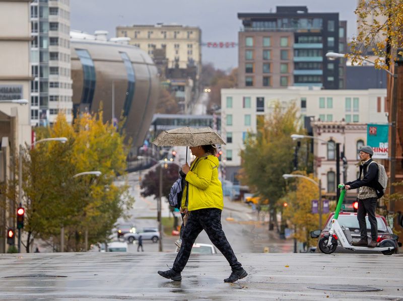 A pedestrian shields themself from the rain with an umbrella as they crowd East Juneau Avenue at North Milwaukee Street in Milwaukee, Wisconsin on Nov. 18, 2025.