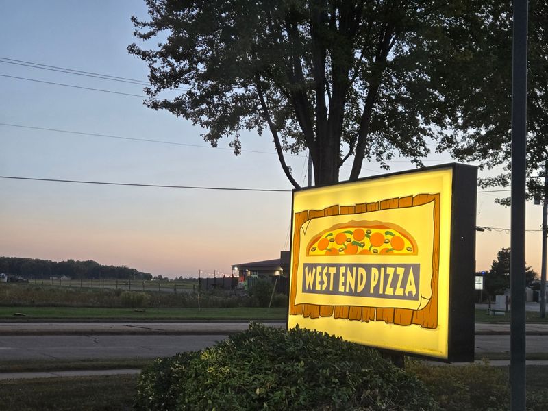 West End Pizza's sign is lit as dusk settles along 20th Avenue in Oshkosh, Wis., as seen in October 2025.