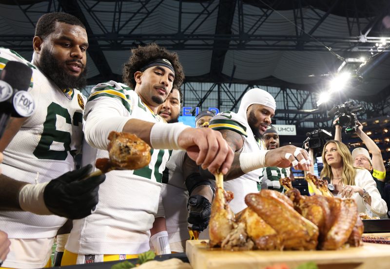 Nov 27, 2025; Detroit, Michigan, USA; Green Bay Packers quarterback Jordan Love (10) and Green Bay Packers defensive end Micah Parsons (1) eat turkey after defeating the Detroit Lions at Ford Field. Mandatory Credit: David Reginek-Imagn Images