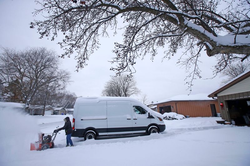 Susan Nagel clears snow in front of her house following a snowstorm Wednesday, December 10, 2025, in Appleton, Wisconsin.