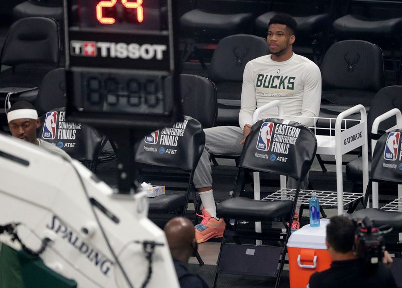 Injured Milwaukee Bucks forward Giannis Antetokounmpo sits on the bench while his teammate warm up before the Eastern Conference finals game against the Atlanta Hawks Thursday, July 1, 2021 at Fiserv Forum in Milwaukee, Wis. Antetokounmpo missed the game with a leg injury.