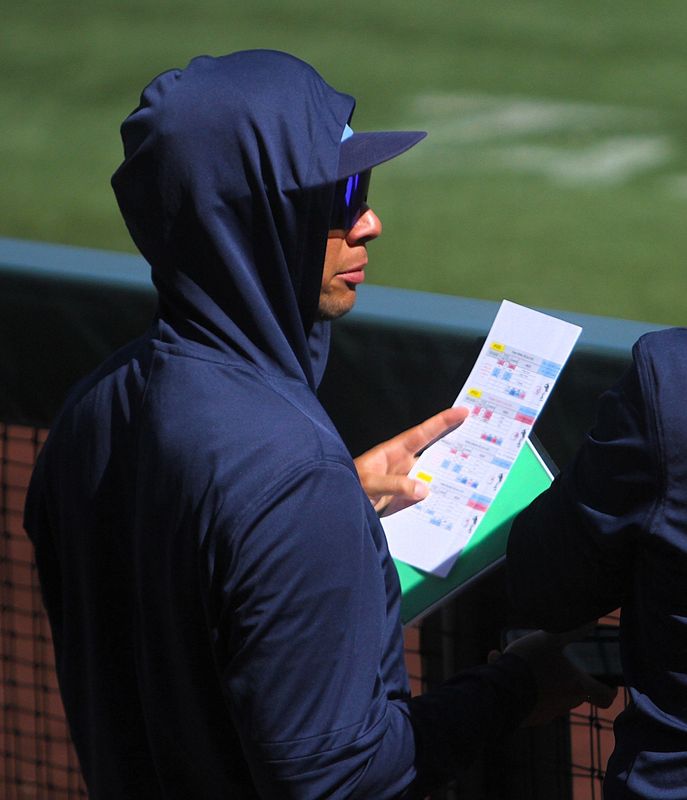 Milwaukee Brewers game preparation specialist Evan Martin holds a green index card to indicate when it's a good situation for players to challenge during a spring training game on March 5, 2026.