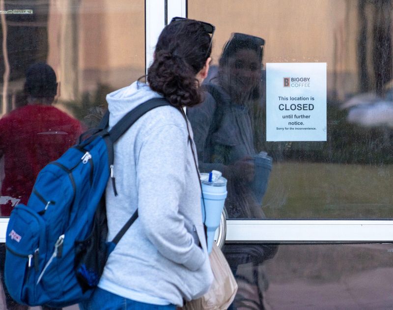 A woman reads a sign on the door of a closed Biggby Coffee in Red Arrow Park in Milwaukee on March 9, 2026.