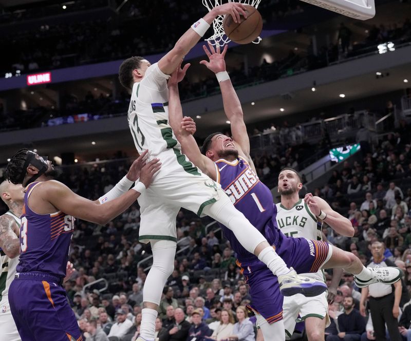 Milwaukee Bucks guard Ryan Rollins (13) and Phoenix Suns guard Devin Booker (1) compete for a rebound during the first half on Tuesday, March 10 at Fiserv Forum in Milwaukee.