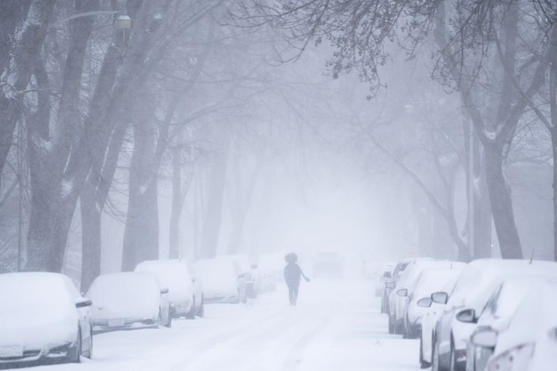 A pedestrian crosses Weil Street in Riverwest during a snowstorm on the morning of March 16, 2026 in Milwaukee, Wisconsin.