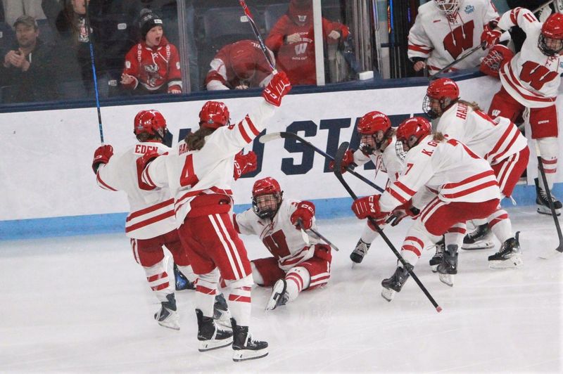 Wisconsin's Kirsten Simms is mobbed by her teammates after scoring the game-winning goal in a 4-3 overtime victory over Penn State in a national semifinal at Pegula Ice Arena in University Park, Pa. on March 20, 2026.