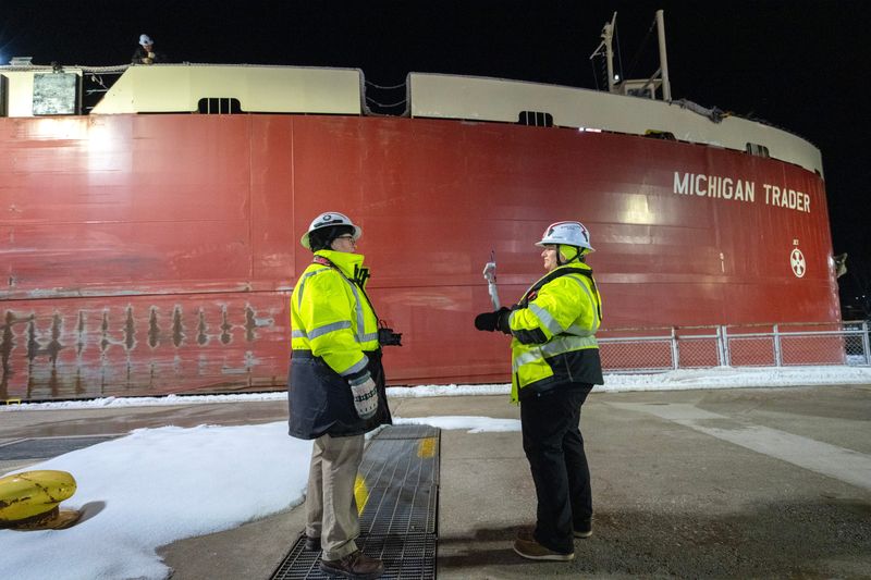 U.S. Army Corps of Engineers Chief Park Ranger Michelle Briggs, left, is interviewed for a Facebook livestream by public affairs specialist Carrie Fox as the 130-foot tug Dirk S. VanEnkevort pushing the barge Michigan Trader, exits the Soo Locks shortly after midnight Wednesday, March 25, 2026, in Sault Ste. Marie, Michigan. The livestream was watched by more than 700 people and will be available for viewing later.