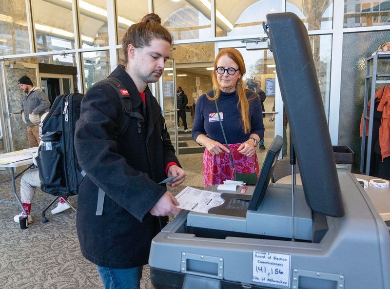 Dan Miller feeds his ballot after voting as poll worker Karen Seigel looks on at the Zeidler Municipal Building on West Broadway in Milwaukee, on April 7, 2026. Voters cast ballots in Wisconsin’s April 7 spring election, which features a statewide race for the Wisconsin Supreme Court, local contests for offices such as mayor and school board, and multiple local referendums across the state.