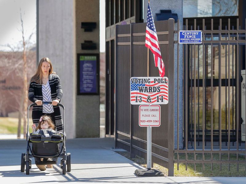 A woman exits Mead Public Library with a child near an election poll, Tuesday, April 7, 2026, in Sheboygan, Wis.