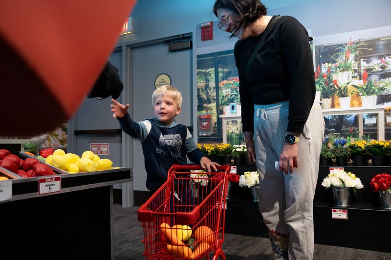 Mason Campbell, 3, accepts a piece of fake fruit from “Baggie” the Sendik’s mascot while shopping with his nanny Kelsey Rhea during the reopening of the Sendik’s Food Market exhibit at the Betty Brinn Children’s Museum on the morning of April 9, 2026 in Milwaukee, Wisconsin.