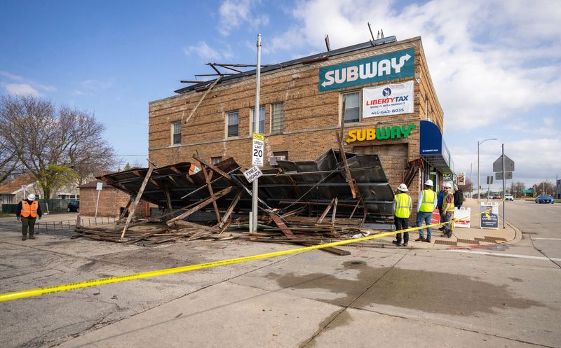 Crews from Lamar sign company work near where a billboard blew off the top of a building on the corner of South 27th Street West Euclid Avenue in Milwaukee, on April 14, 2026. Severe storms blew through the early Tuesday causing damage and power outages.